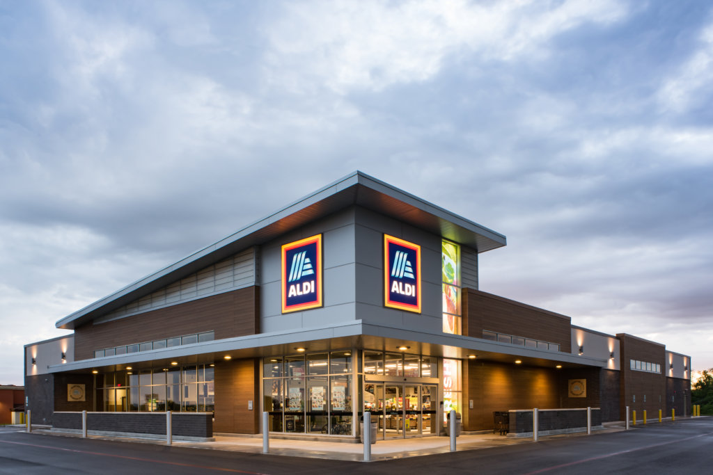 The exterior of an Aldi grocery store with the lights on designed by SGA Design Group.